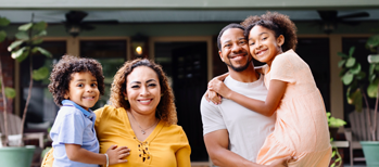 Family posing for a photo in front of a house.